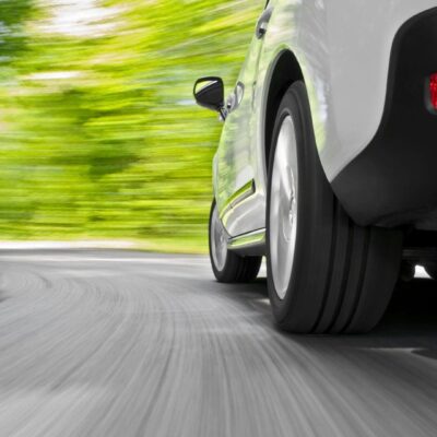 A car driving down a road with trees in the background.