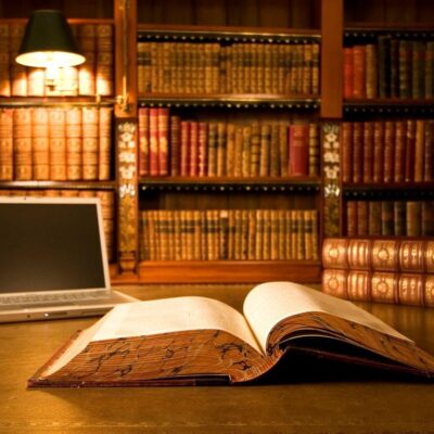 An open book and laptop on a table in a library.