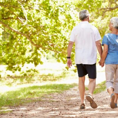 An older couple walking down a path in a park.