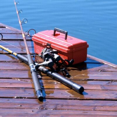 Two fishing rods and a fishing case on a wooden dock.