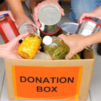 A group of people putting food into a donation box.