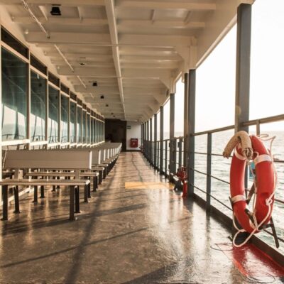 The deck of a ferry with benches and a life preserver.