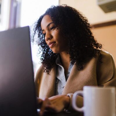 A woman working on a laptop in a coffee shop.