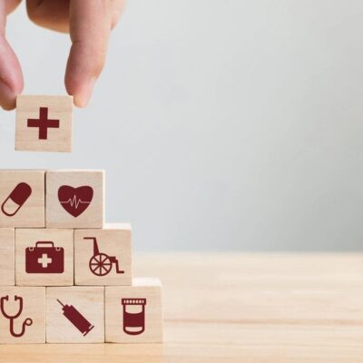 A hand is holding wooden blocks with medical icons on them.