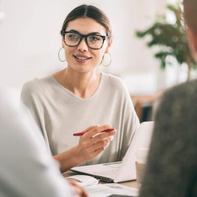 Woman in glasses leads business meeting.