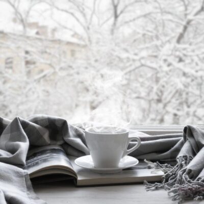 A cup of coffee and a book on a window sill.