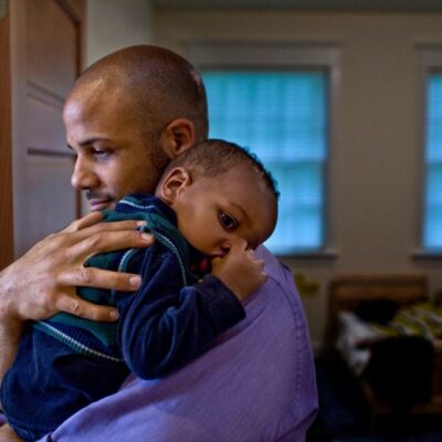 A man lovingly hugging a child indoors.