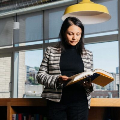 A woman reading a book in a library.