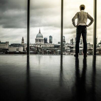 A businessman looking out of a window at london's skyline.