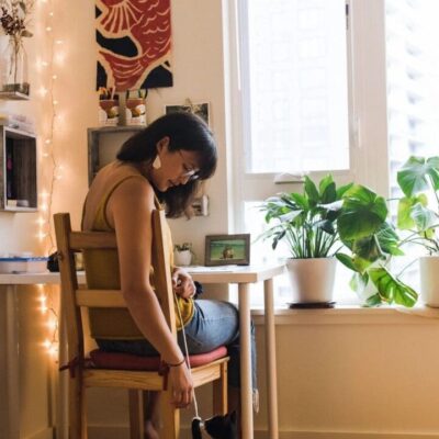 A woman sitting on a chair with a black cat in front of her.