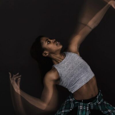 A woman in a plaid shirt is dancing on a black background.