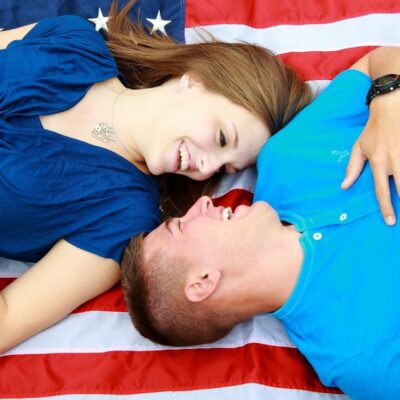 A man and woman laying on an american flag.