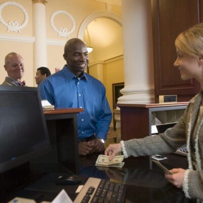 A man and woman at the counter of a hotel.