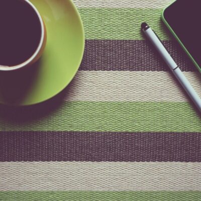 A cup of coffee next to a cell phone.