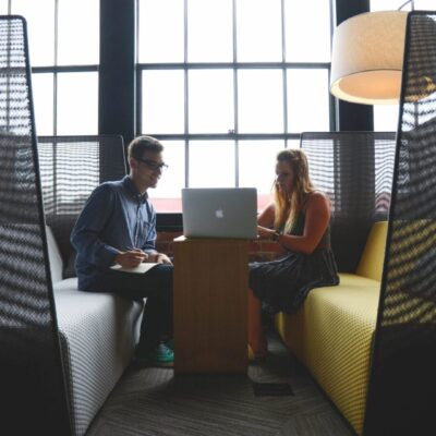 Two people sitting in an office with a laptop.