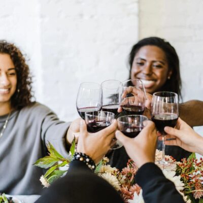 A group of people toasting wine glasses at a dinner table.