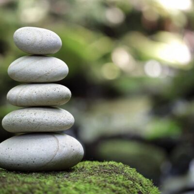 Stacked smooth stones balanced on mossy ground.