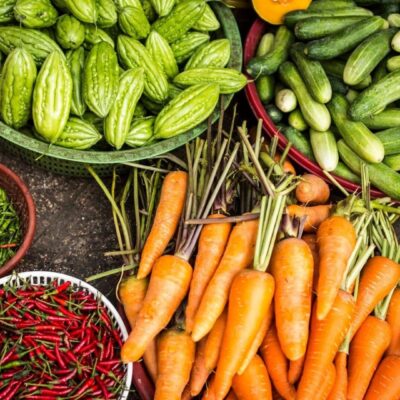 Fresh carrots, cucumbers, and chilies arranged at a market stall.