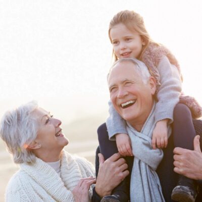 An older couple and a little girl are having fun on the beach.