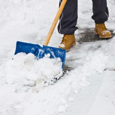 A man shoveling snow with a blue shovel.