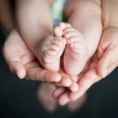 A pair of hands holding a baby's feet.