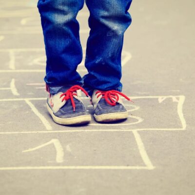 A child's feet standing on a hopscotch board.