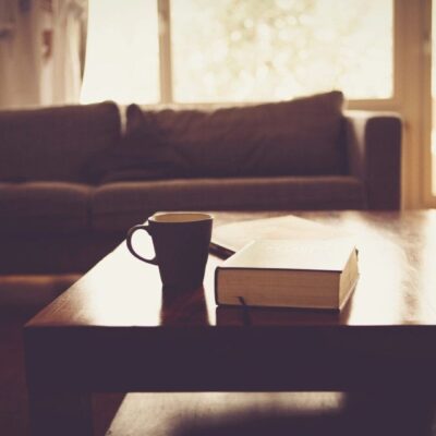 A coffee cup and book on a table in a living room.