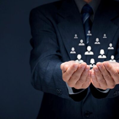 A businessman is holding up a group of people in his hands.