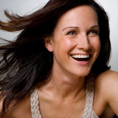 A joyful woman with flowing hair smiling brightly.