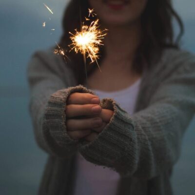 A woman holding a sparkler in her hand.