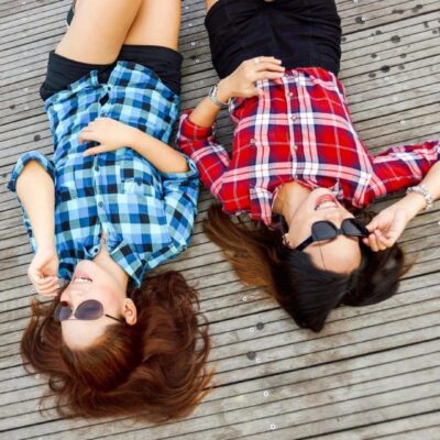 Two young women laying on a wooden deck.