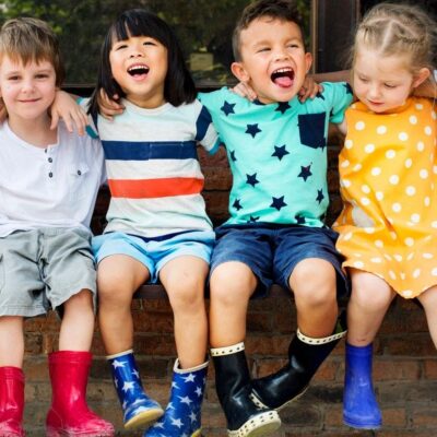 Children sitting together, smiling, wearing colorful outfits.