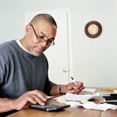 A man sitting at a table with papers and a calculator.