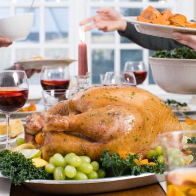 A turkey is sitting on the table with grapes.