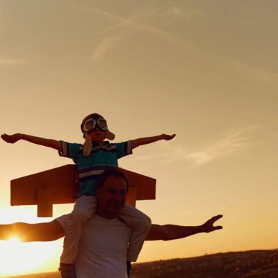 A man is holding a plane on his shoulders at sunset.