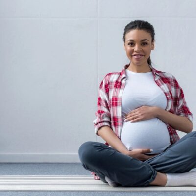 A pregnant woman sitting on a yoga mat.