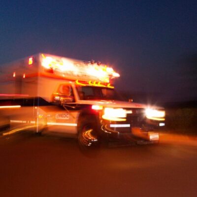 An ambulance driving down the road at night.