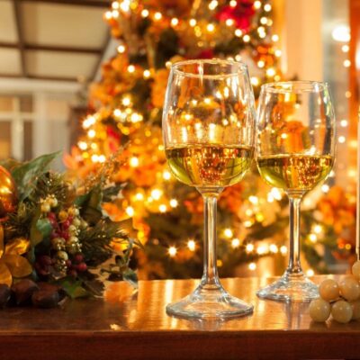 Two wine glasses are on a table in front of a christmas tree.