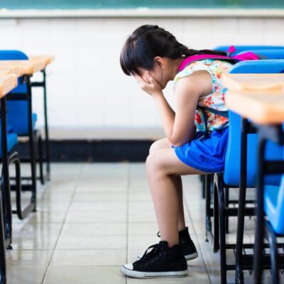 A young girl sitting in an empty classroom.