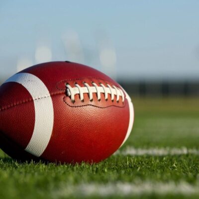 A close-up of an American football on a grassy field.