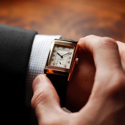 A man in a suit is holding a watch.
