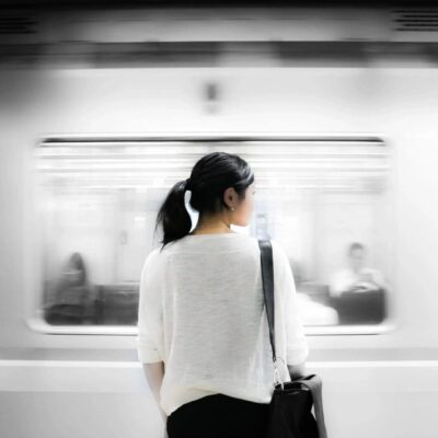 A woman standing in front of a train.