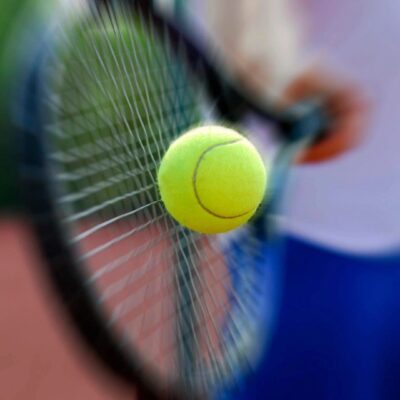 A person is holding a tennis racket and a ball.