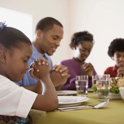 Family praying before Thanksgiving meal.