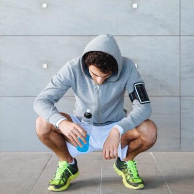 A man squatting down holding onto something