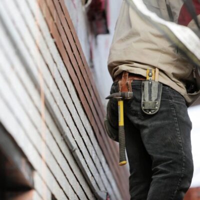 A construction worker is holding a tool on the side of a building.