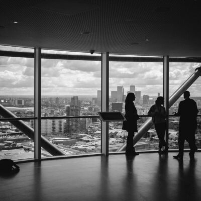 A group of people standing in front of a large window overlooking a city.