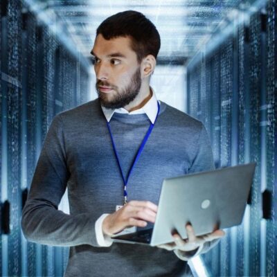 Man with laptop in server room.