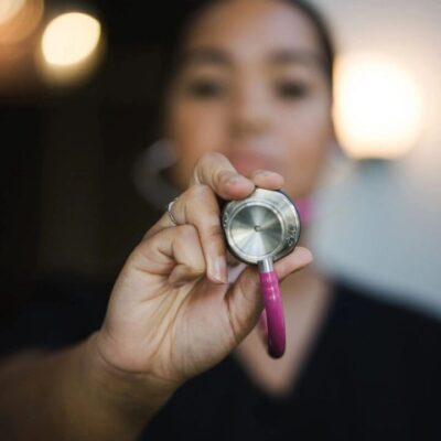 A nurse holding a pink stethoscope.
