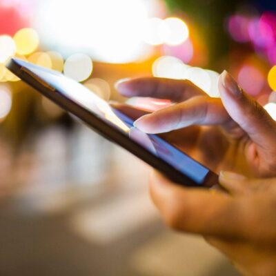 Here's a suitable alt tag: Hands using smartphone at night.